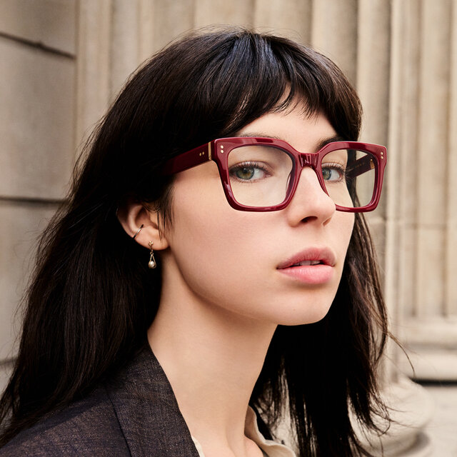 Model wearing a red square acetate frame stocked by Bramley Pope