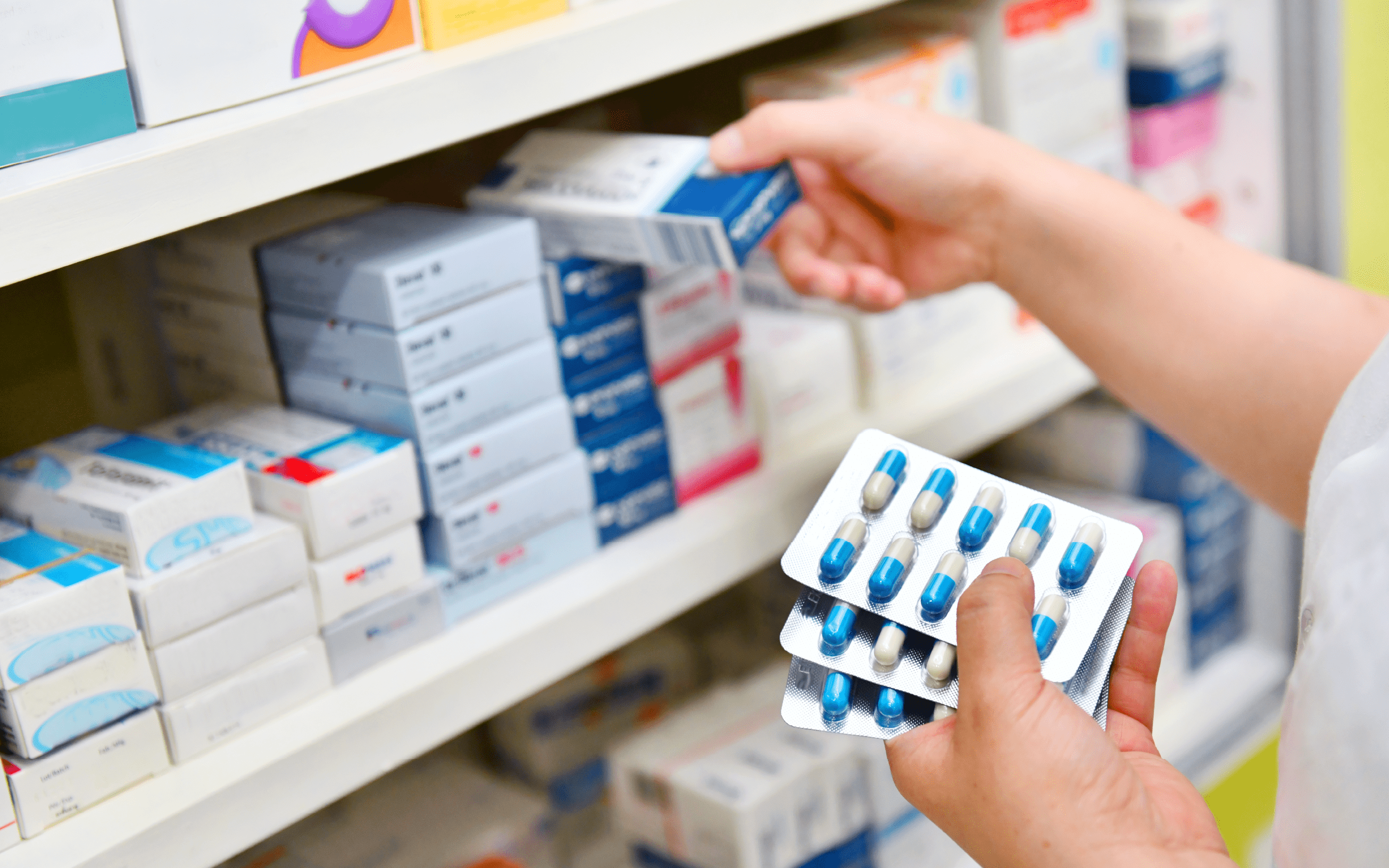 Hero banner image — generic stock photo of hands selecting medicine boxes from a shelf (not the actual premises)