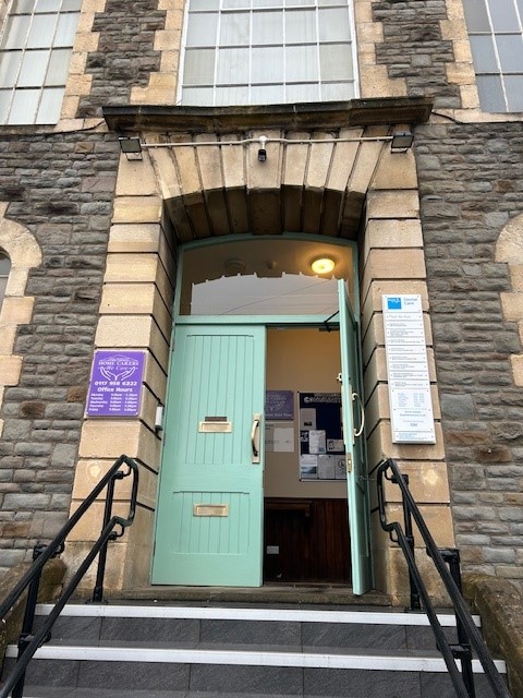 Main entrance doorway with green door and stone arch