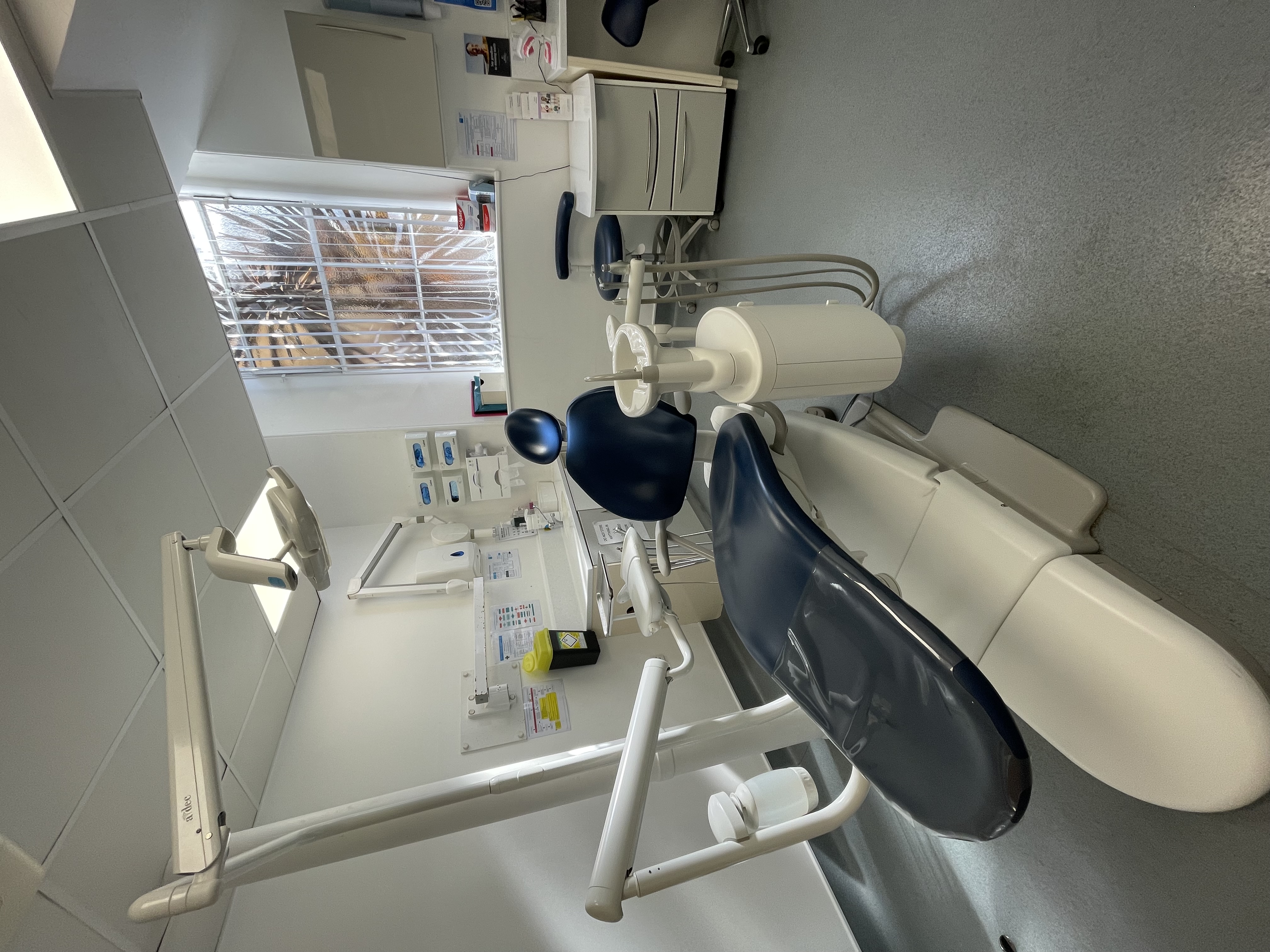 Treatment room with a dark-blue dental chair, light and instrument tray
