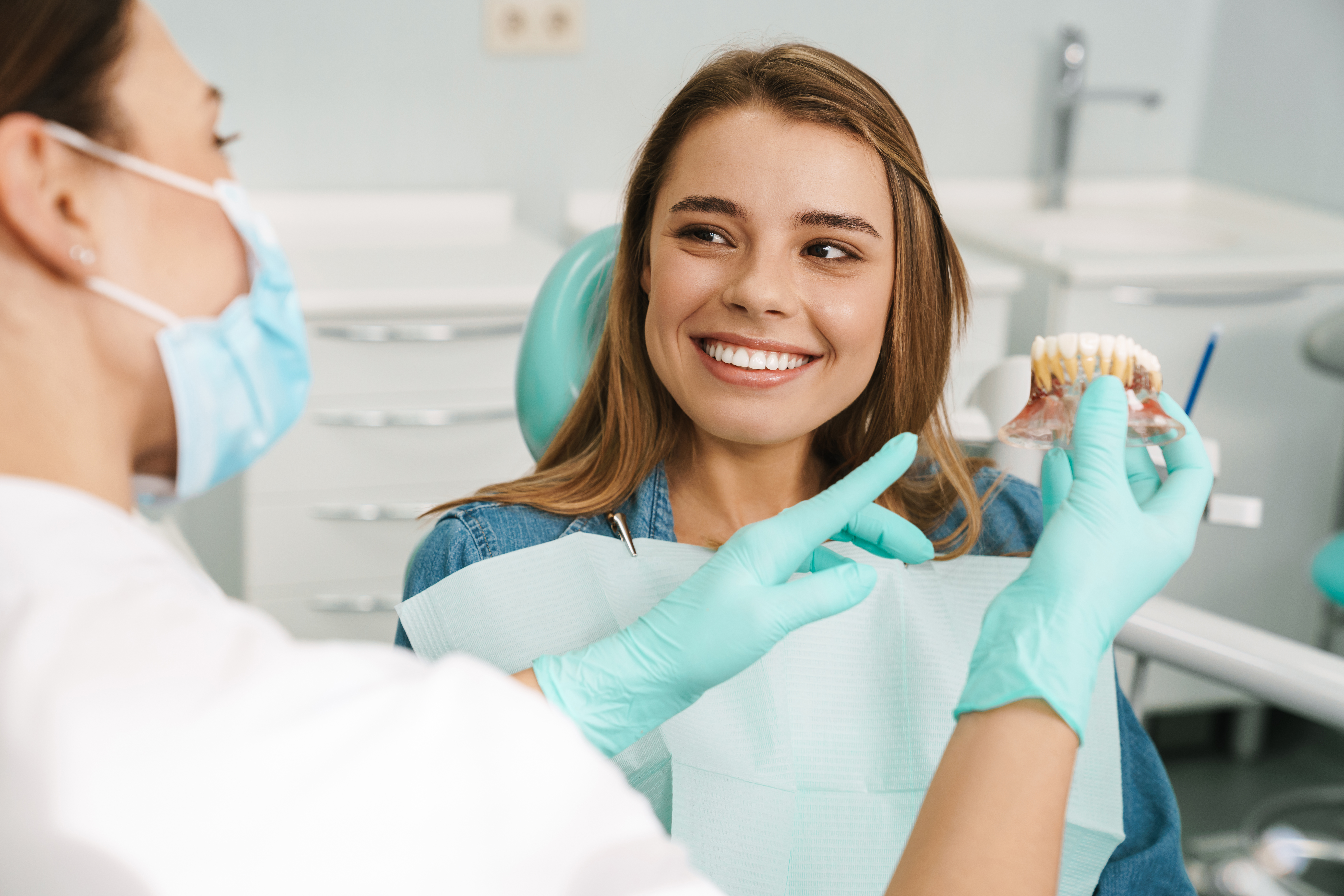 Dentist showing teeth model to a smiling patient in the dental clinic