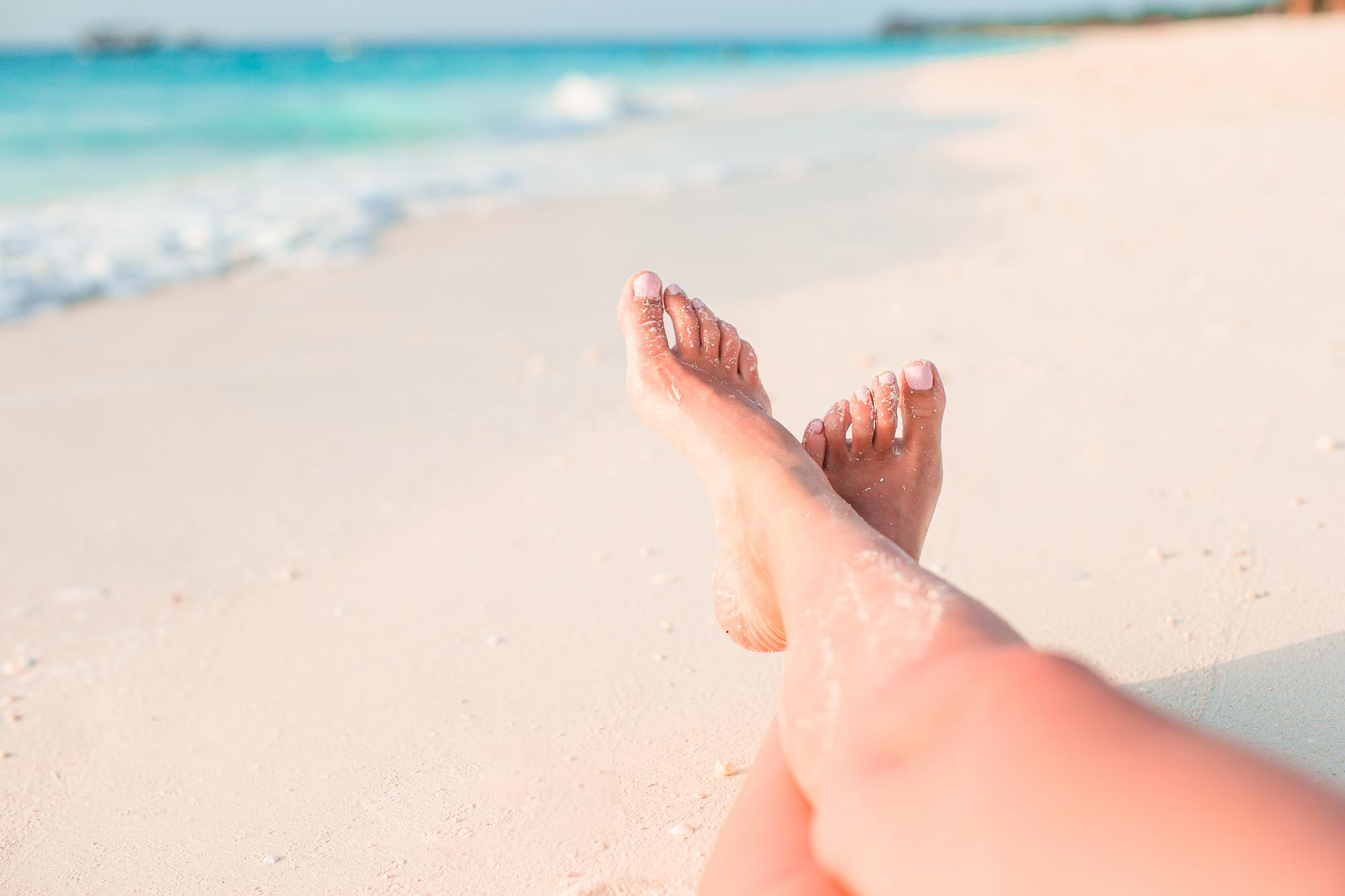 Woman's feet on beach sand - podiatry related imagery