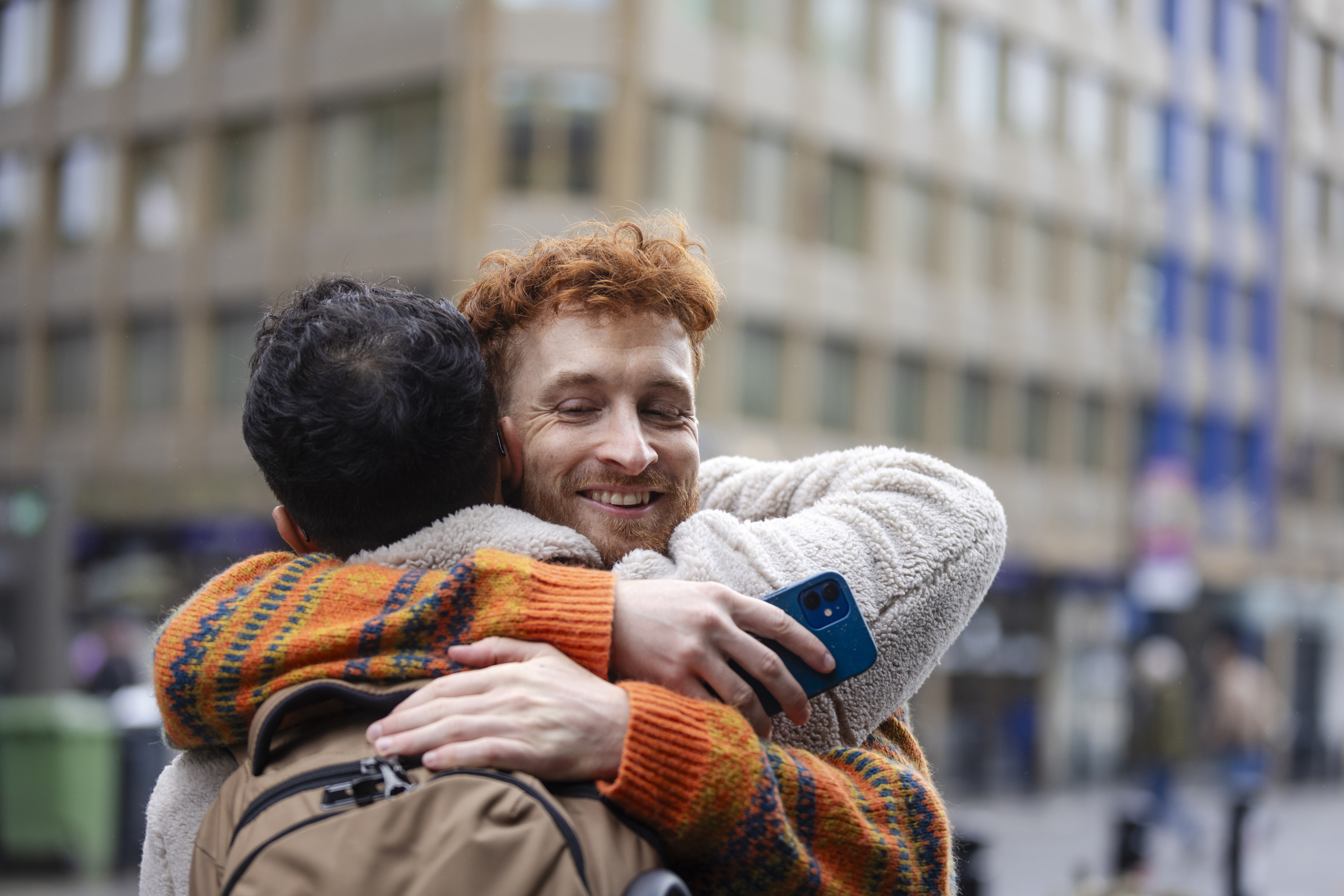 Two friends hugging in a city