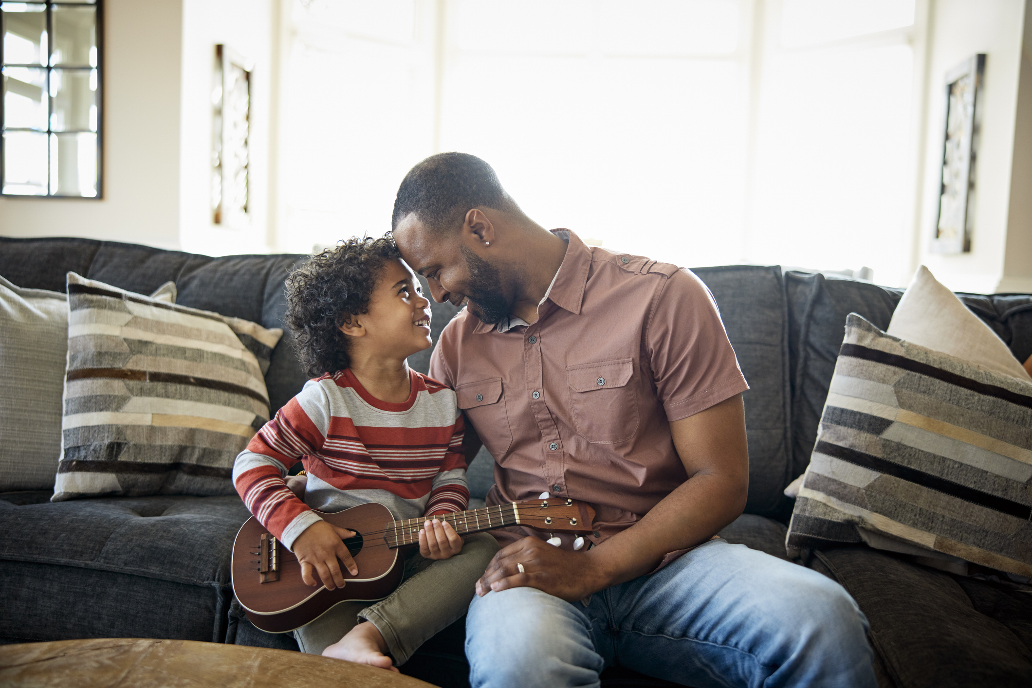 Father and son sitting on sofa with a guitar