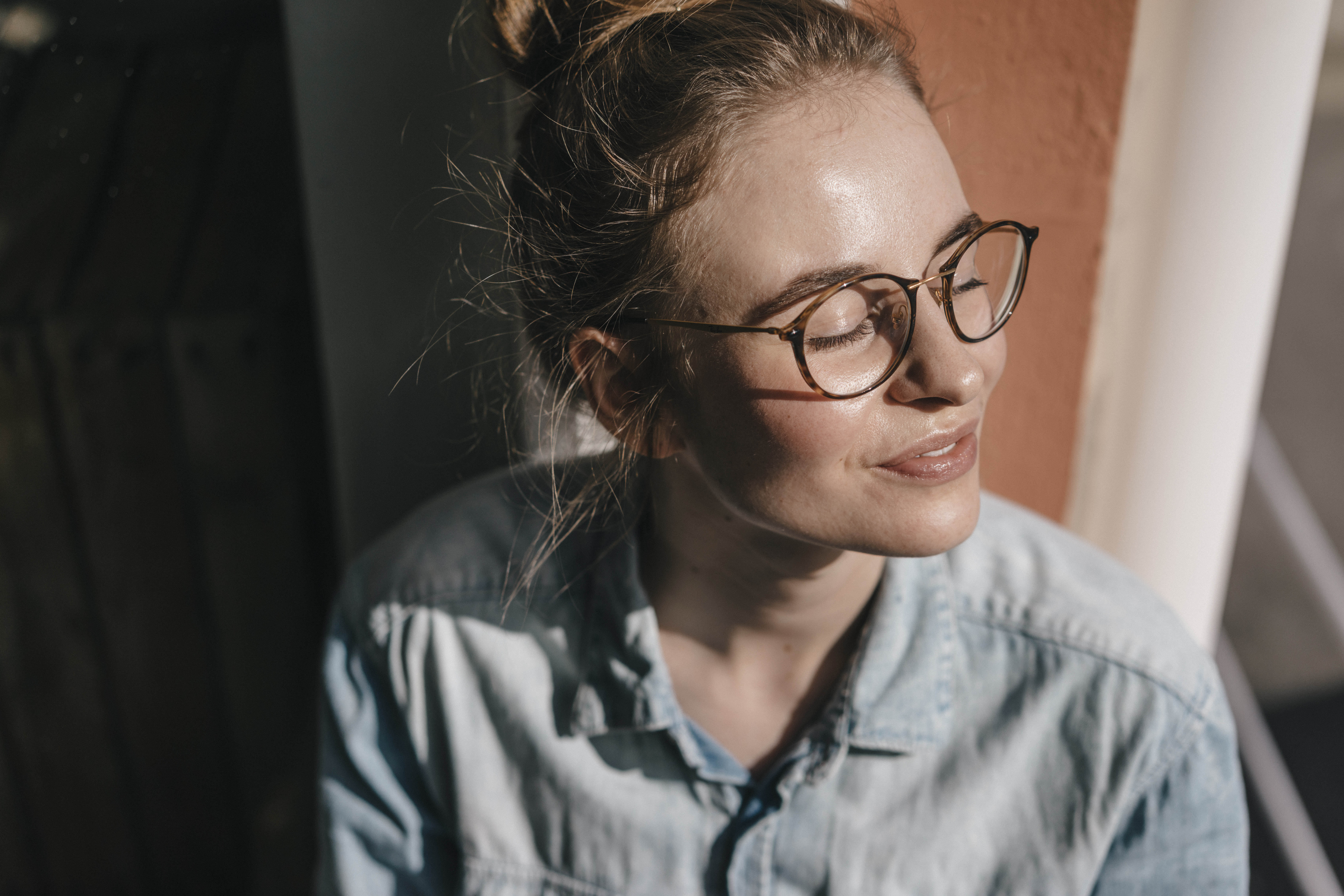 Woman wearing glasses looking towards the sun with eyes closed