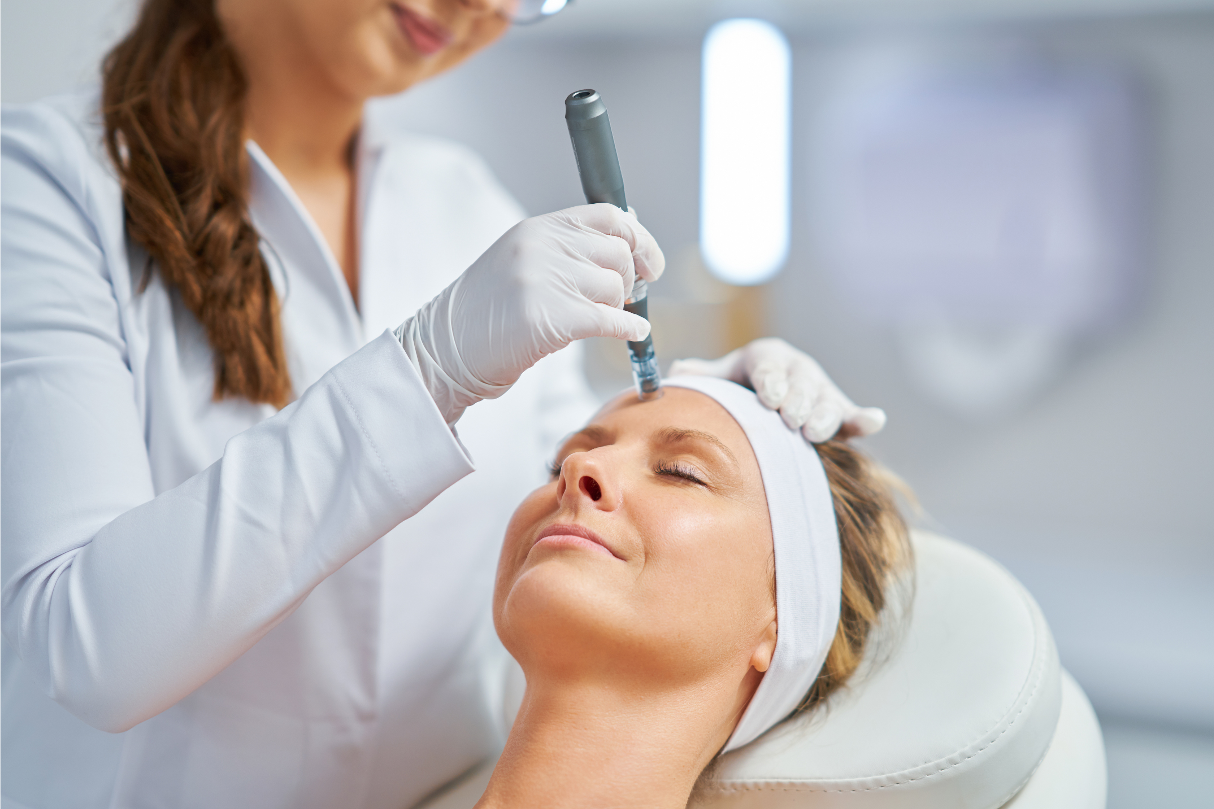 A happy, relaxed woman receiving a microneedling treatment