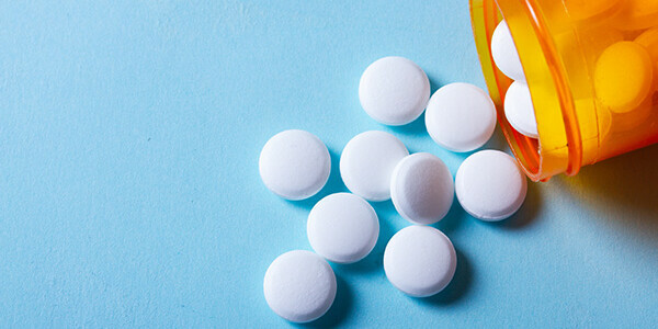 Homepage tile: Prescriptions (white round pills in orange bottle stock image)