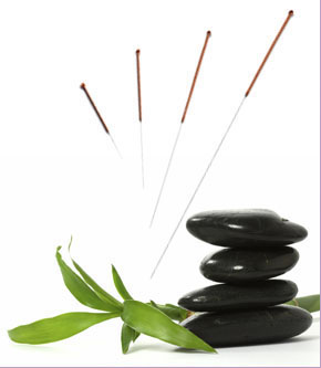 Acupuncture needles arranged over stacked black stones and bamboo