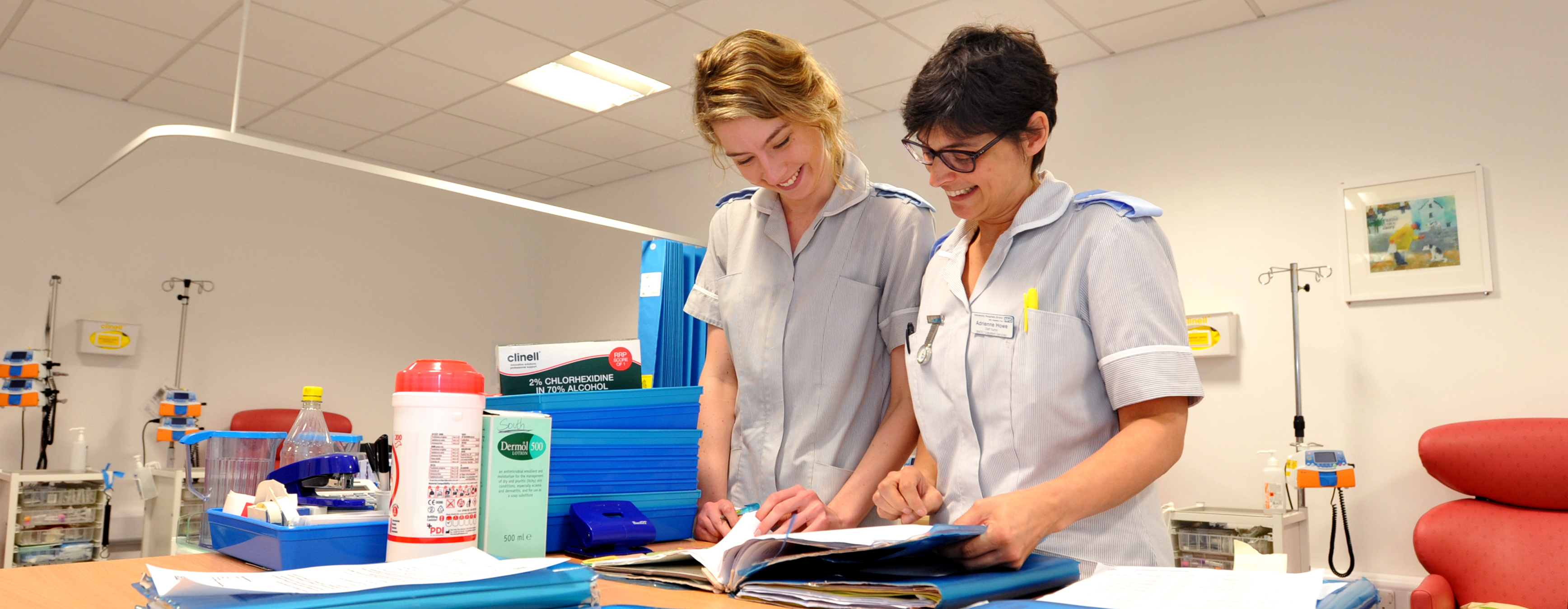 Two therapy staff reviewing notes in a rehabilitation treatment room